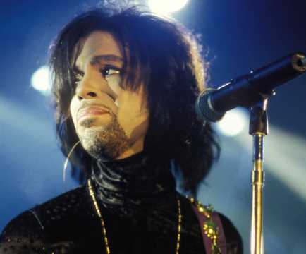 Prince, the singer, performing on stage looking sentimental.