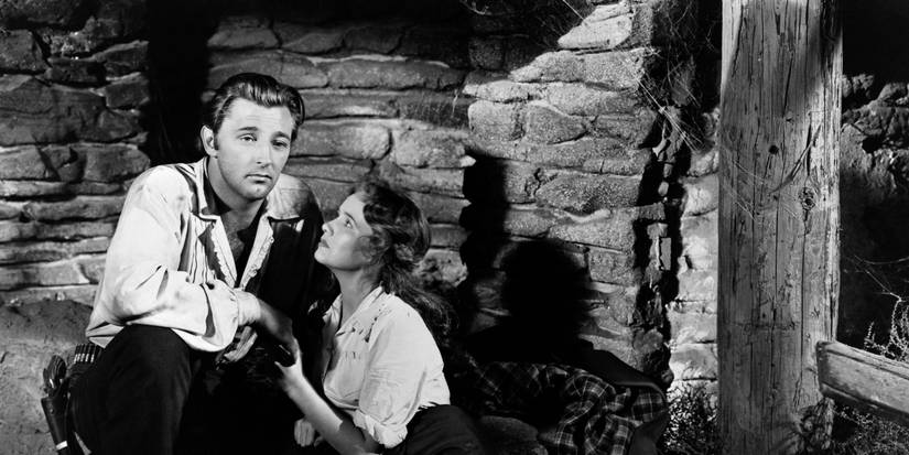 Robert Mitchum kneeling and Teresa Wright sitting down and looking up at him in Pursued.