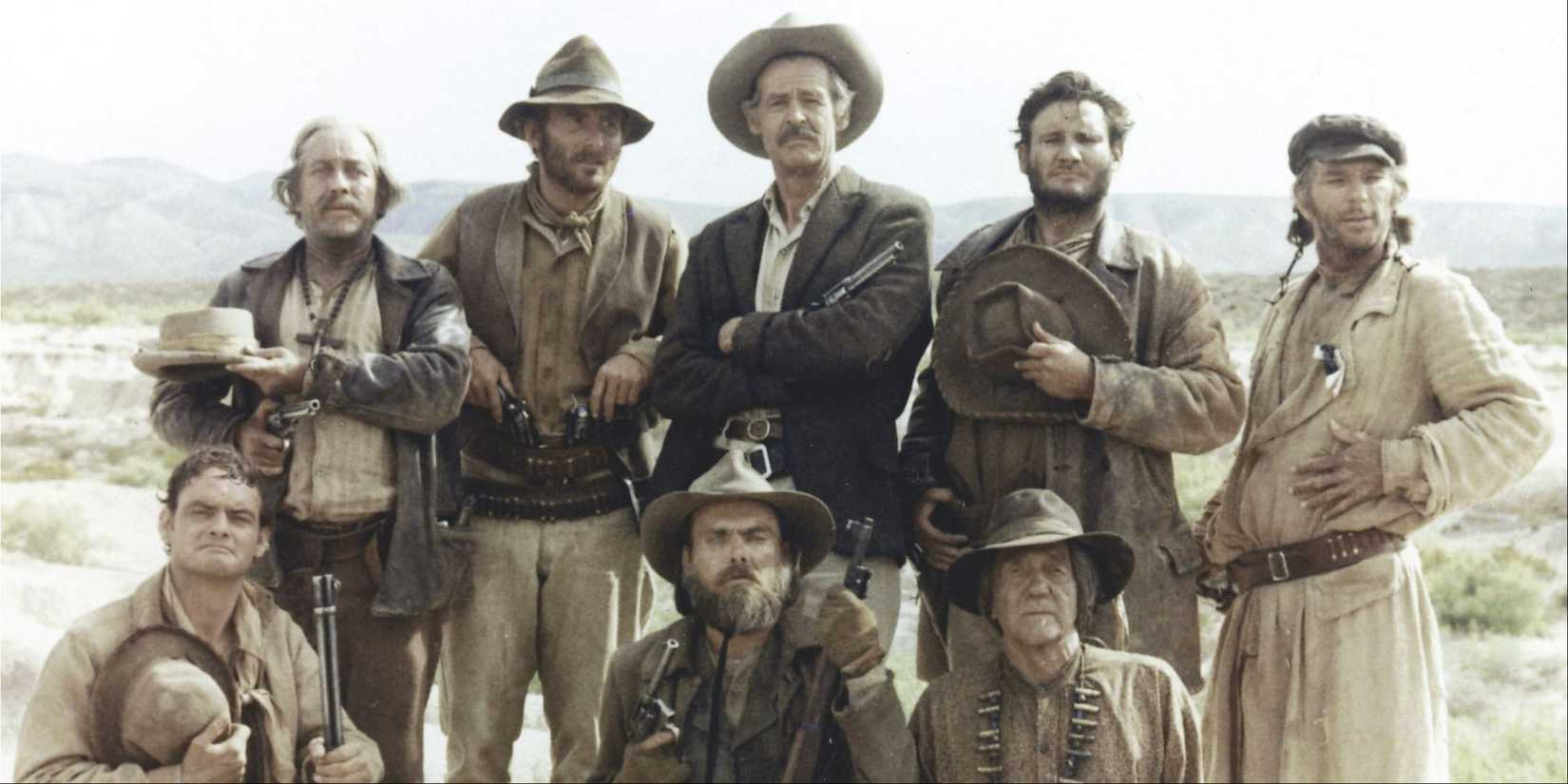 The cast of The Wild Bunch in ragged western apparel, outdoors looking towards the camera.