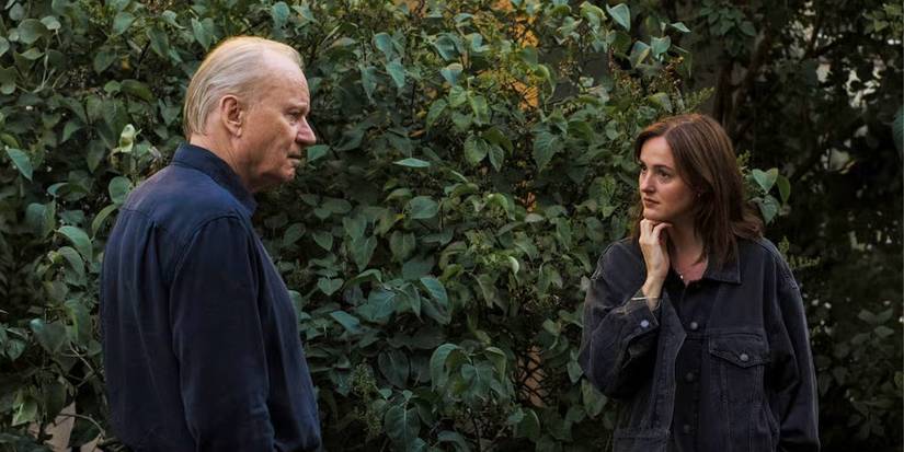 Gustav and Nora in conversation outside near a bush in Sentimental Value.