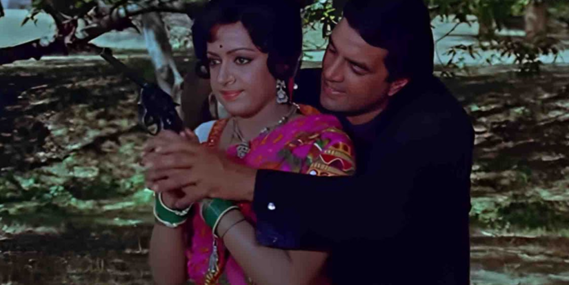 Dharmendra standing behind a woman helping her hold a gun in Sholay