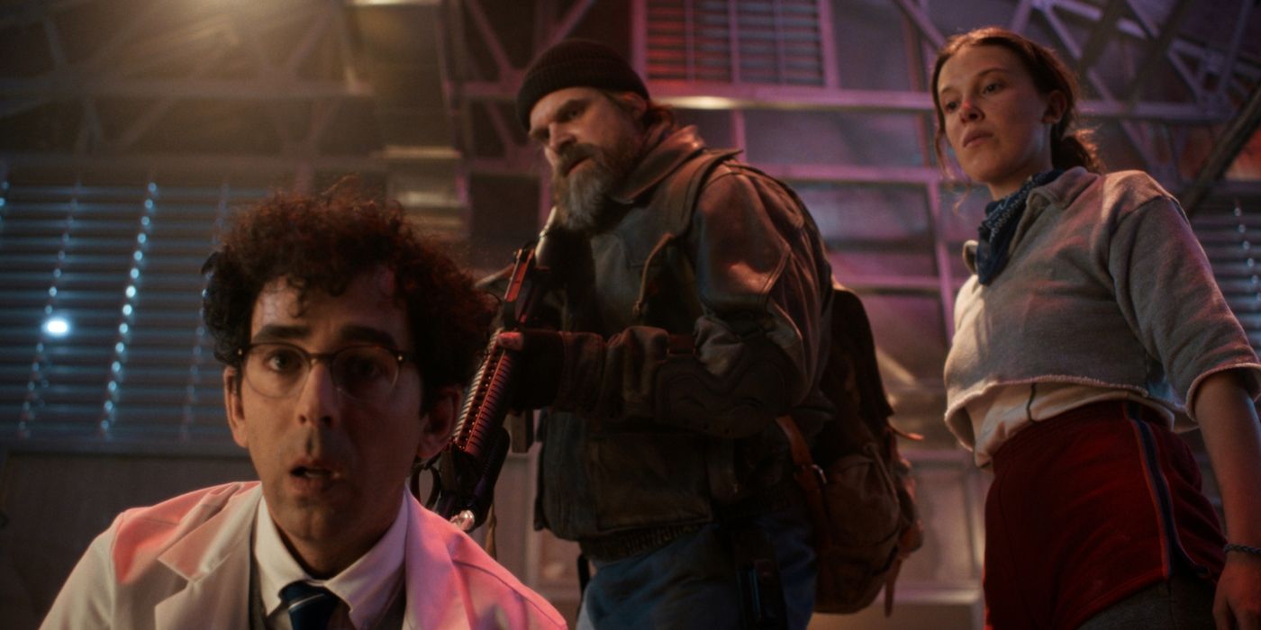 Jesse Gavin as a military base scientist being held at gunpoint by David Harbour as Hopper and Millie Bobby Brown as Eleven in 'Stranger Things' Chapter 5.