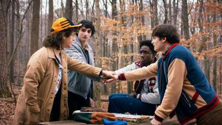 The OG Stranger Things party: Dustin, Mike, Lucas, and Will put their hands together while outside.