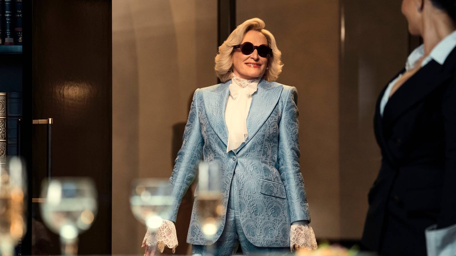 Glenn Close walks in the room in sunglasses and an elaborate suit in All's Fair
