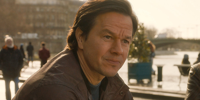Mark Wahlberg wears a brown jacket and looks off camera in The Family Plan 2