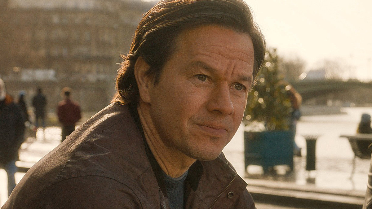 Mark Wahlberg wears a brown jacket and looks off camera in The Family Plan 2