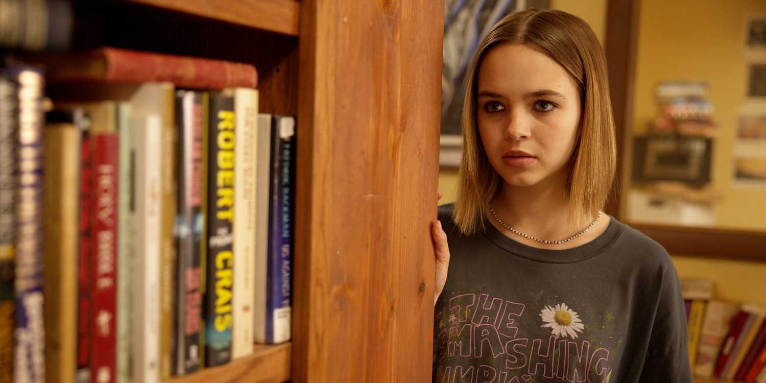 Ryan Kiera Armstrong as Francis leaning against an aisle of books in her father's bookstore in The Lowdown