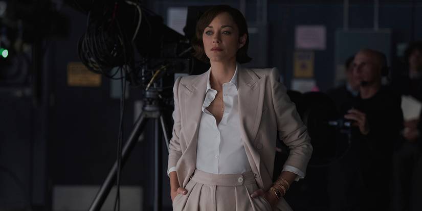 Stella standing with her hands in her pockets in The Morning Show.