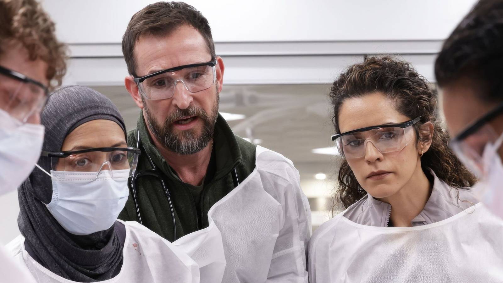 Doctors, including Noah Wyle, in scrubs surround an off-camera patient in The Pitt.