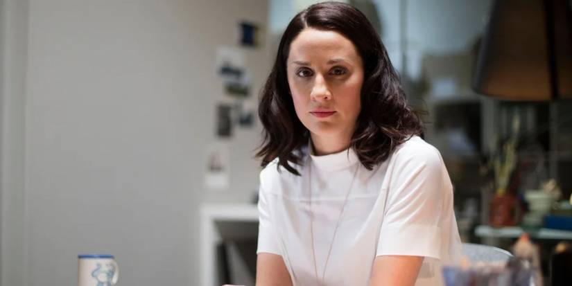 Morven Christie as Ellen Rooney sitting at a table with a serious expression in The Replacement.