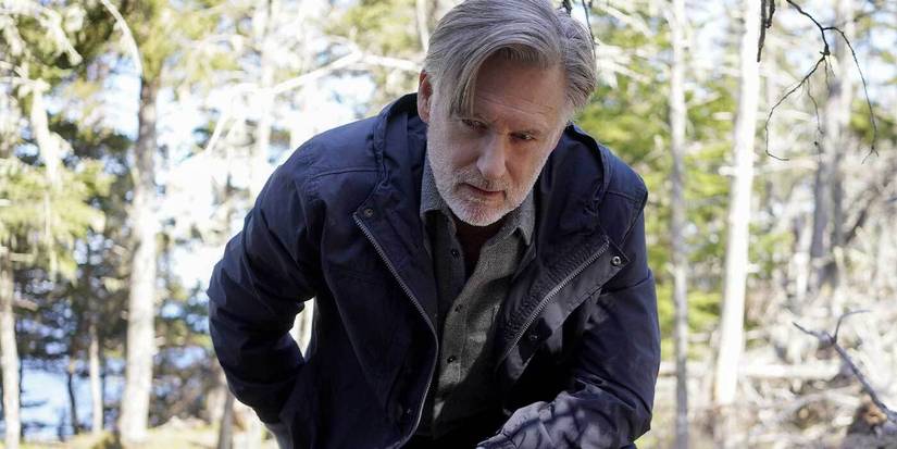 Bill Pullman leaning over in the woods in The Sinner
