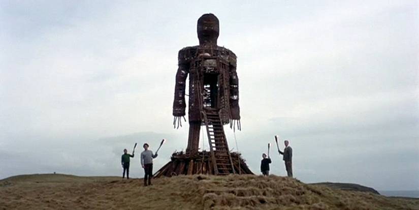 People standing next to a large wooden stick figure in The Wicker Man