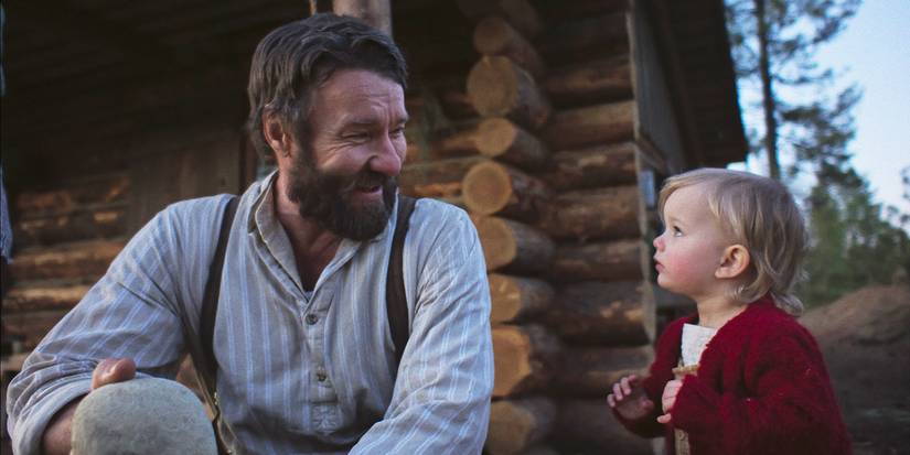 Robert Grainier smiles over at his little girl outside their cabin in Train Dreams.