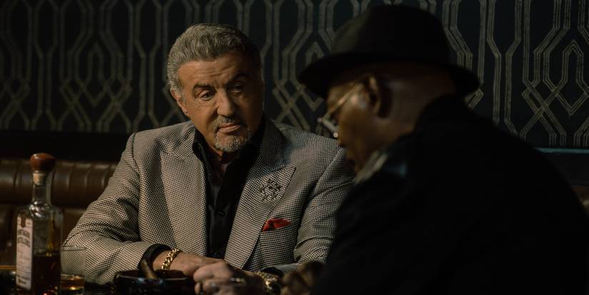 Sylvester Stallone and Samuel L. Jackson talking at a table in Tulsa King Season 3, Episode 9.