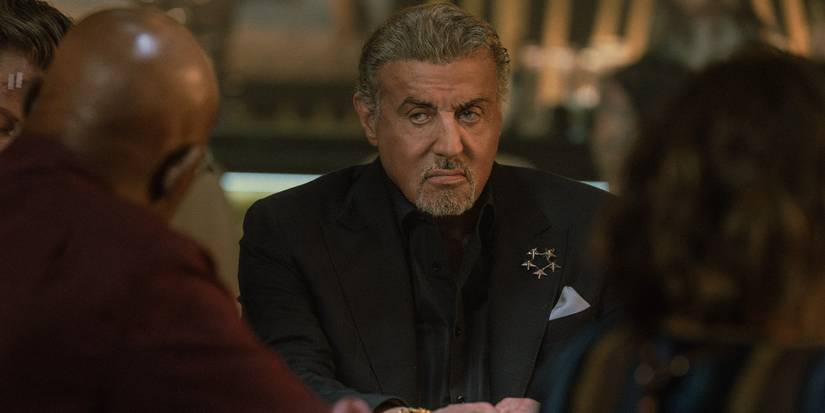 Sylvester Stallone looking at two people across from him seriously in the Tulsa King Season 3 finale.