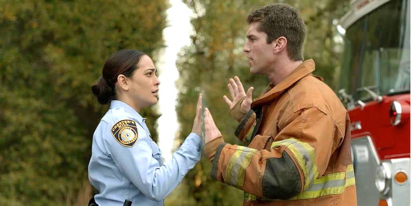 Deputy Linda and her fiancé Rusty hold hands up, separated by an invisible wall in Under the Dome.