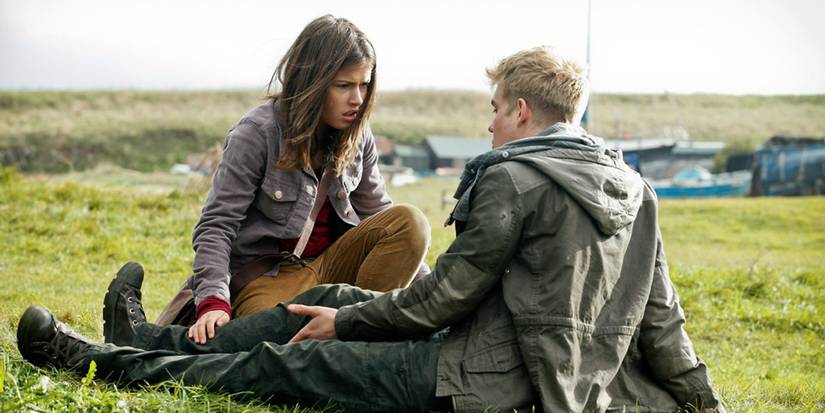 Maddy kneeling next to Rhydian as he sits on the ground in Wolfblood