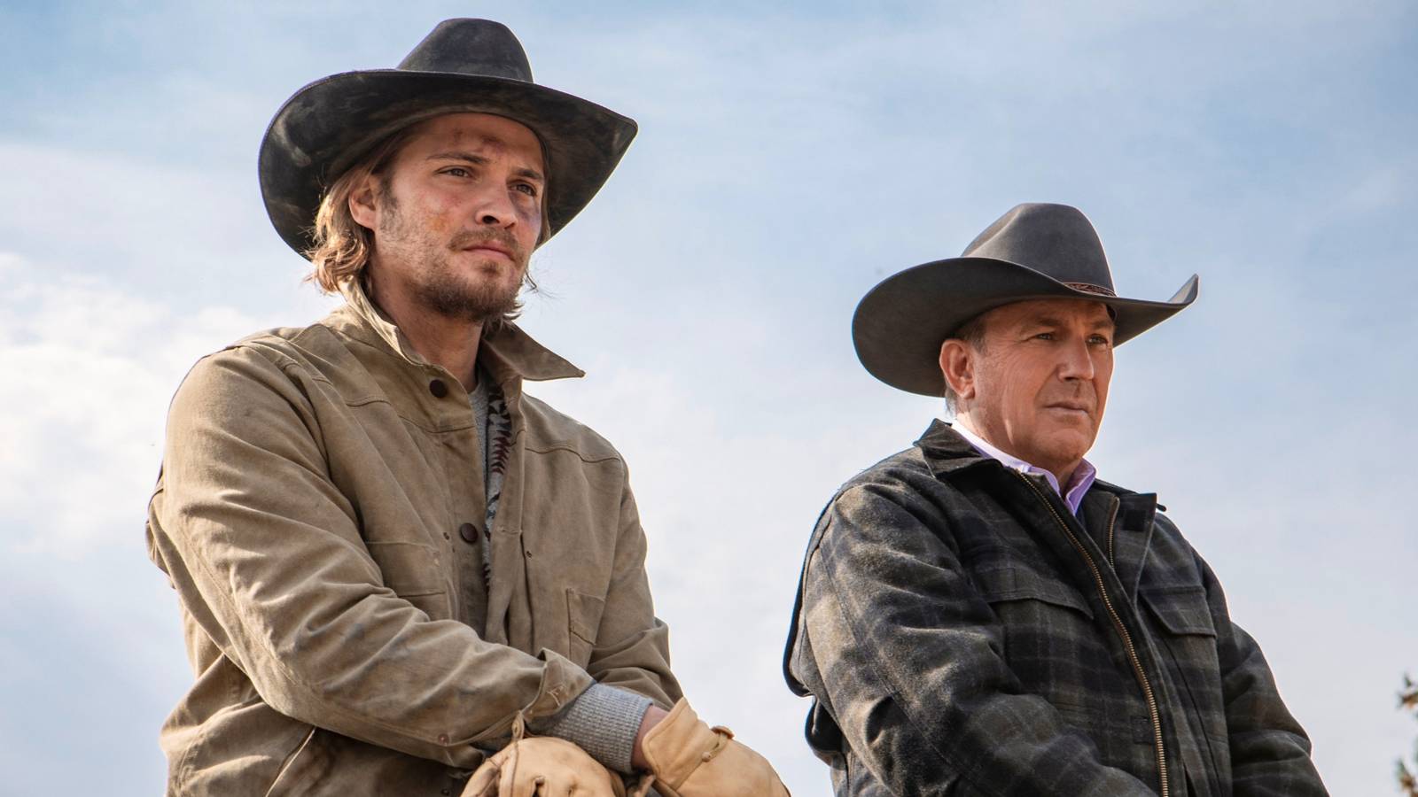 Luke Grimes and Kevin Costner in western apparel looking to the distance in Yellowstone.