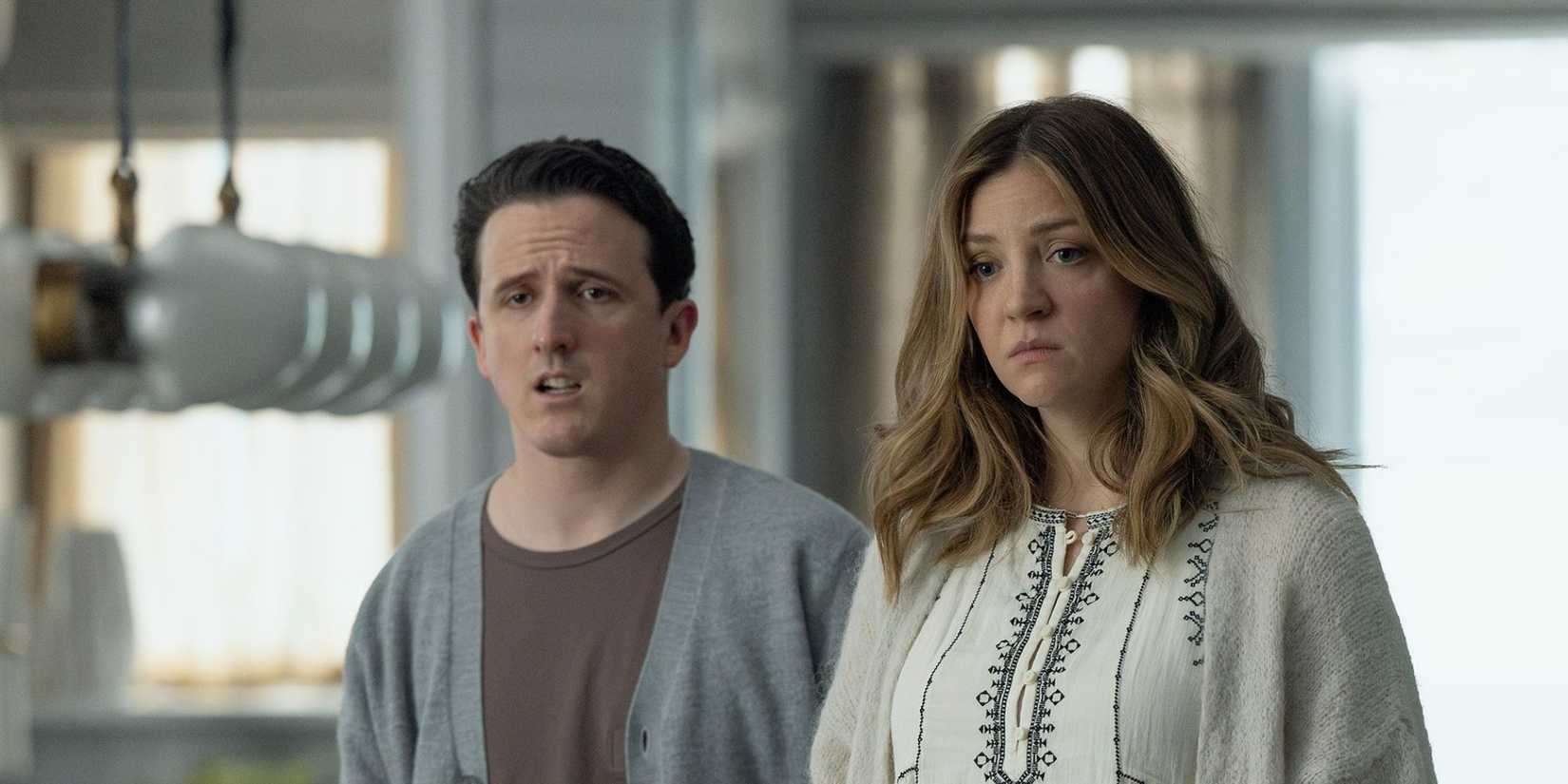 Daniel Monks as Brian stands near Abby Elliott as Lia looking ahead, worried in All Her Fault.