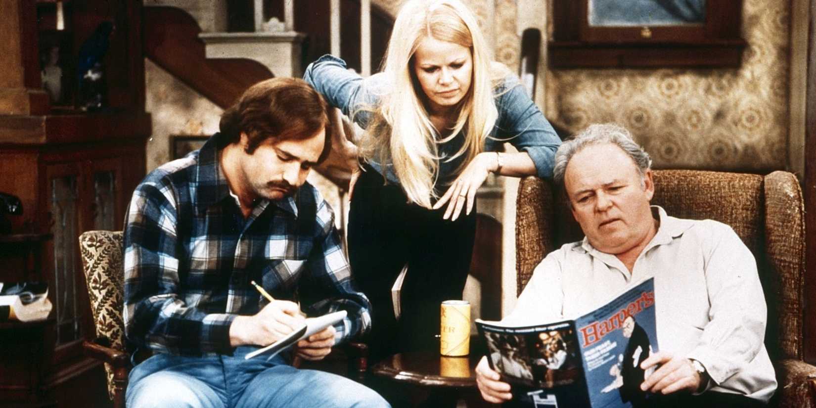 Rob Reiner writes in a notebook next to two other cast in All in the Family.