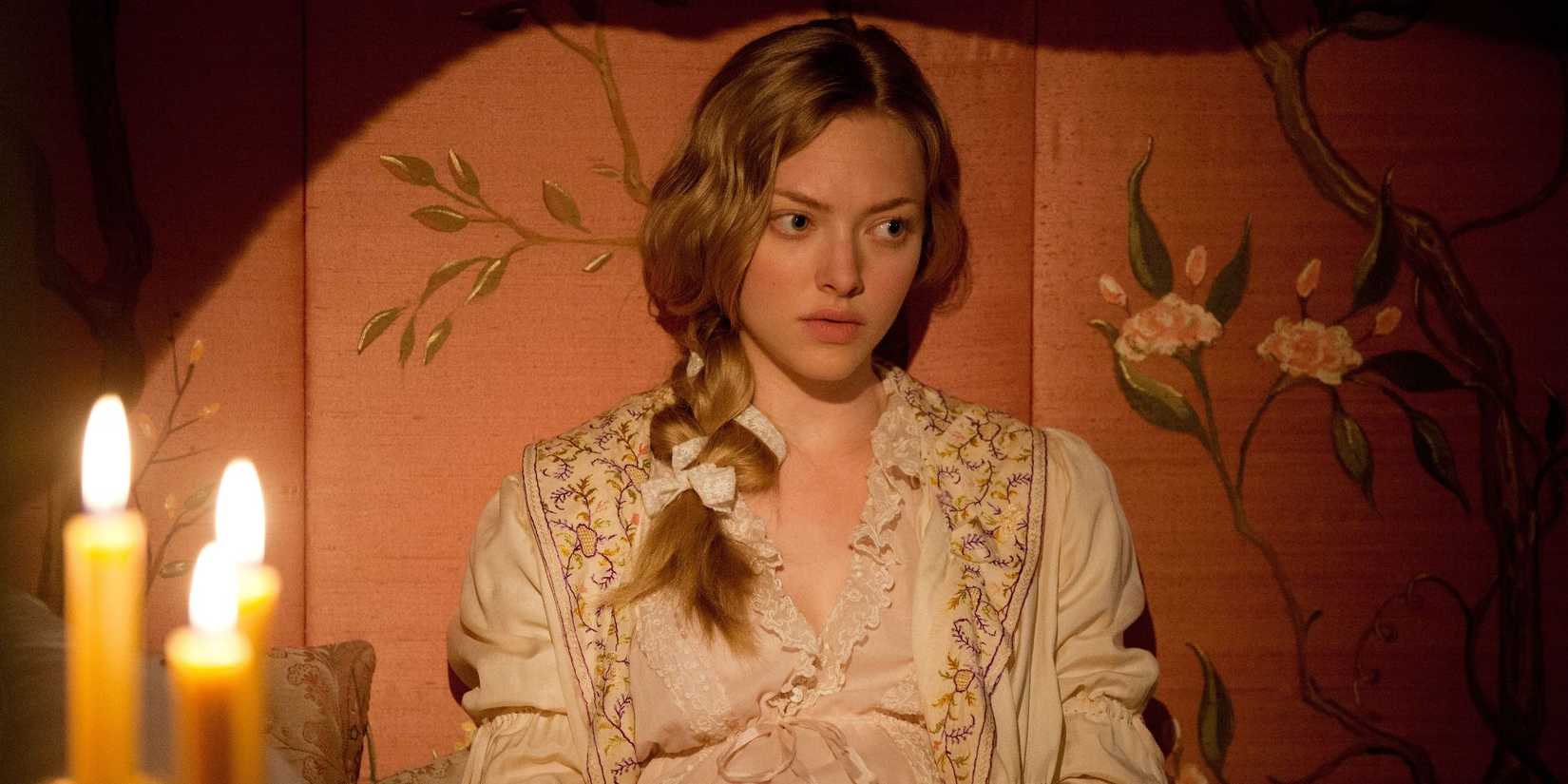 Amanda Seyfried as Cosette leaning against the wall and looking pensive in Les Misérables.