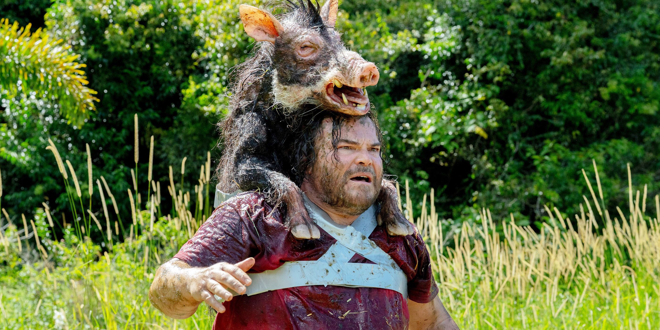 Doug is standing in a field with a dead boar strapped to his back.