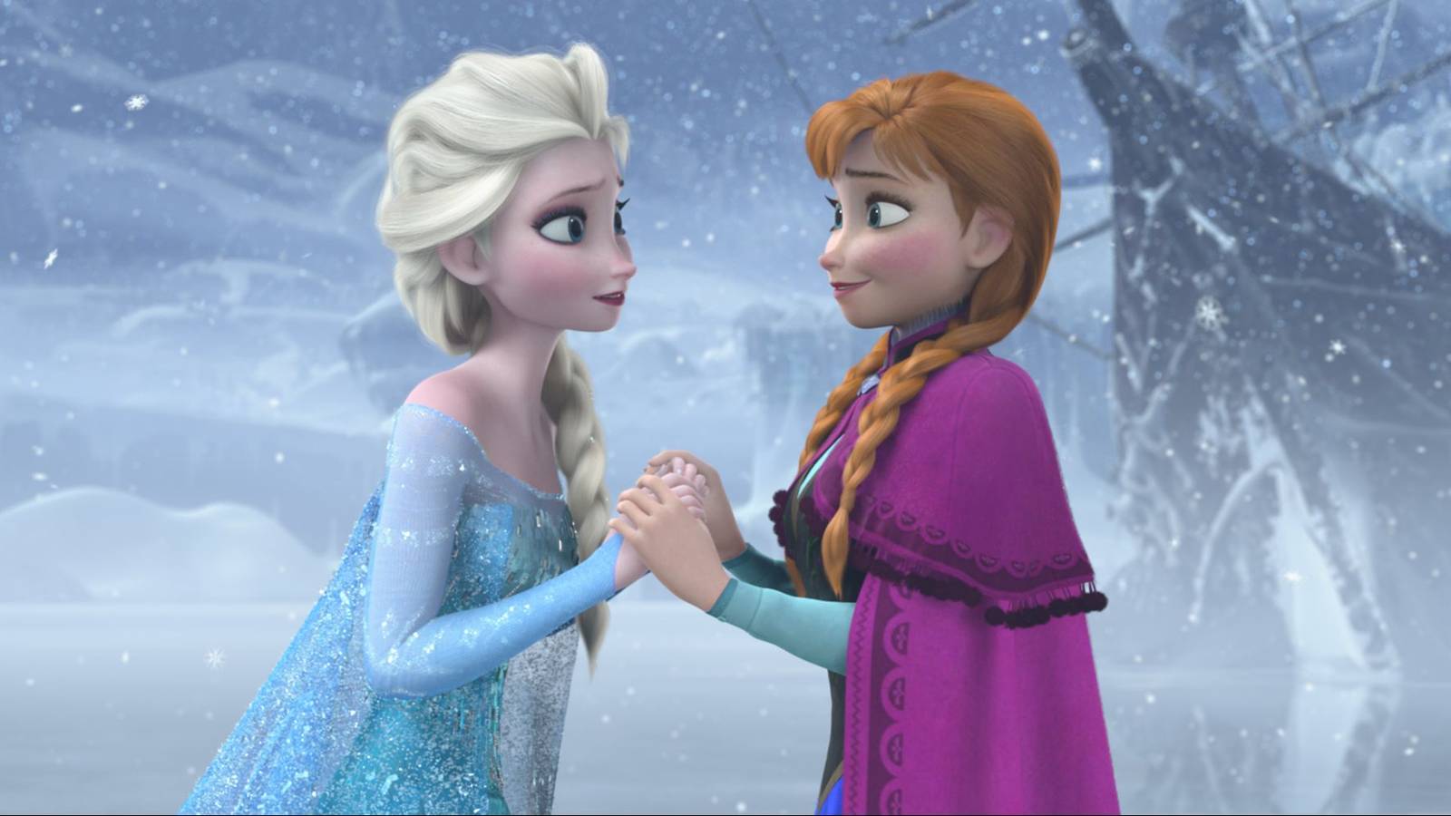 Anna and Elsa hold hands and smile at each other, standing on a frozen lake in Frozen.