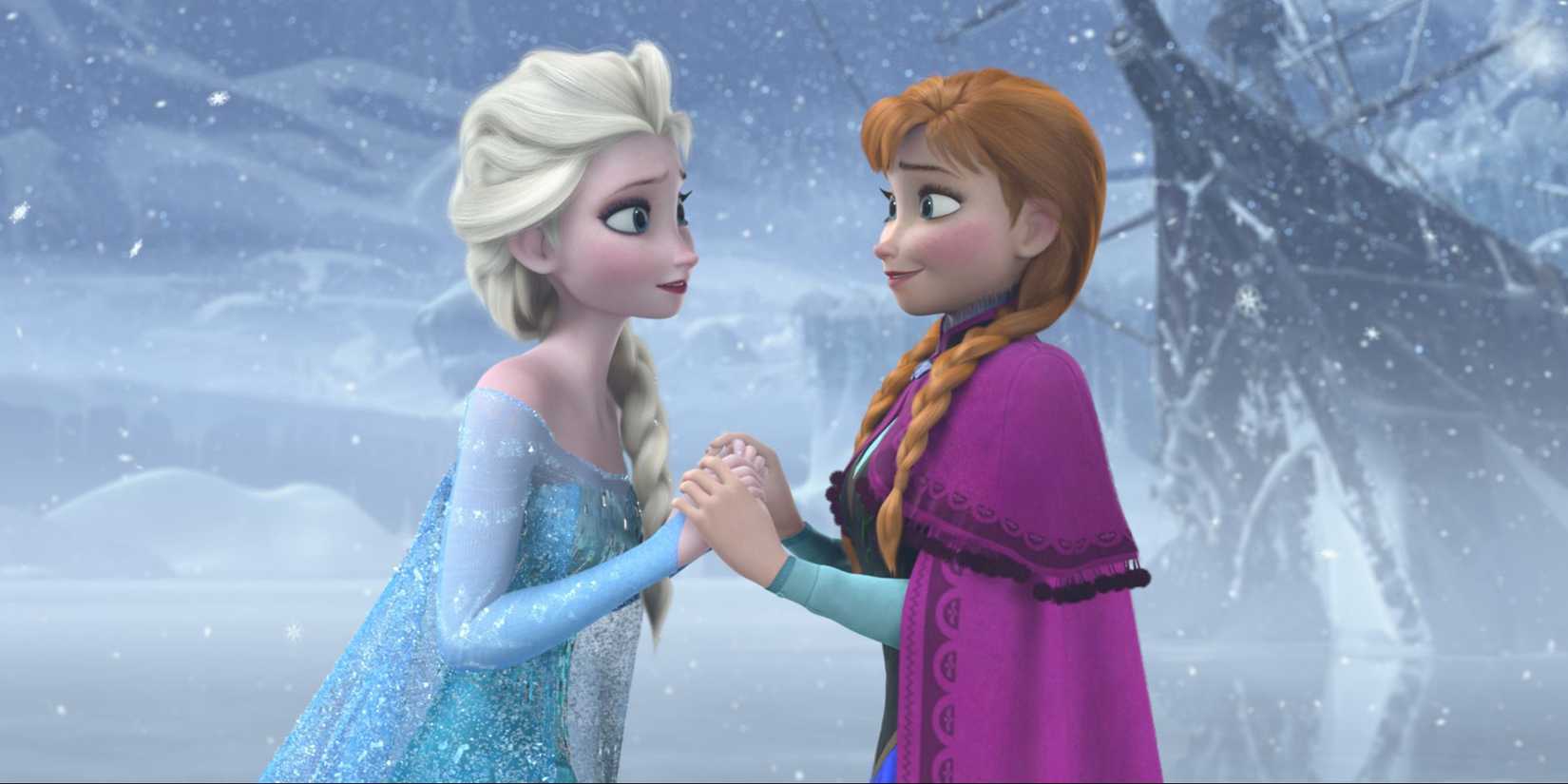 Anna and Elsa hold hands and smile at each other, standing on a frozen lake in Frozen.