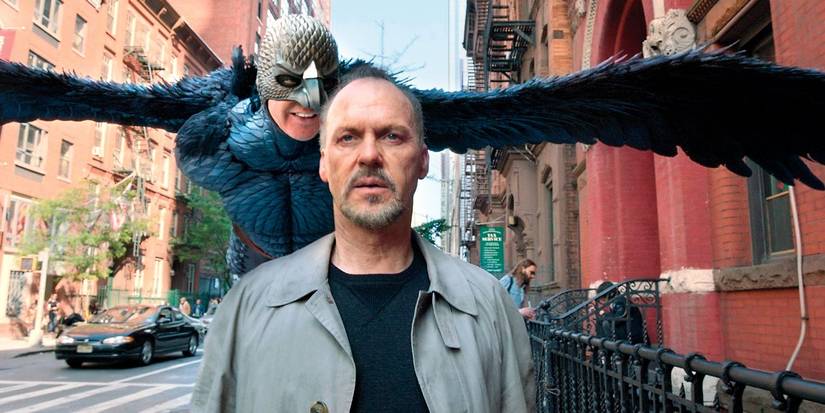 Riggan (Michael Keaton) walking down the street with his famous character, Birdman, flying behind him in 'Birdman'