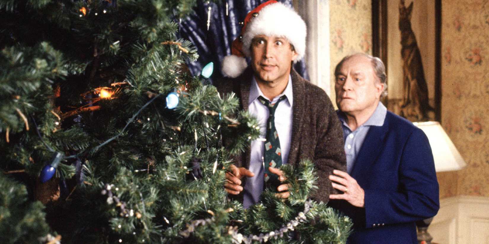 Chevy Chase as Clark and E.G. Marshall as Art hide behind a tree in National Lampoon's Christmas Vacation.