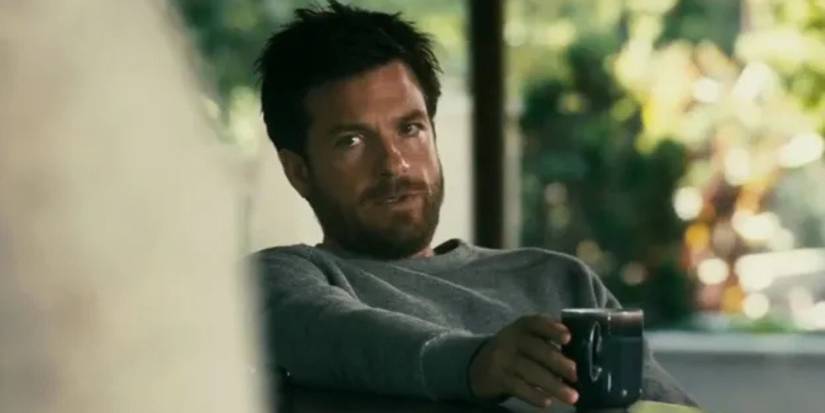 Jason Bateman as Rich Boyd with a scruffy beard sits and looks to the side with a cup in Disconnect.