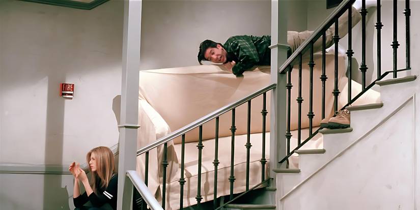 Ross (David Schwimmer) tries to get his couch unstuck while Rachel (Jennifer Aniston) sits nearby in Friends