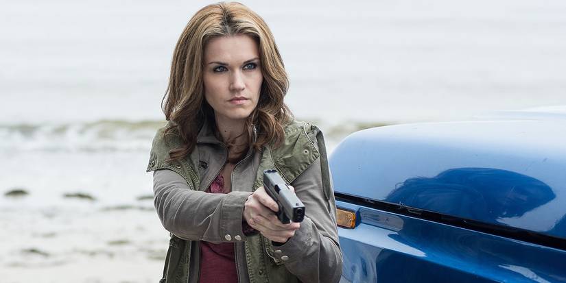 Emily Rose holding a gun outside next to a vehicle during the day on Haven.