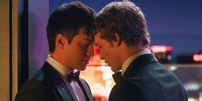 Connor Storrie and Hudson Williams in tuxedos with their heads together tenderly in Heated Rivalry.