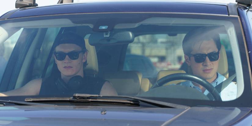 Connor Storrie and Hudson Williams sitting in a car with sunglasses on in Heated Rivalry Episode 6.