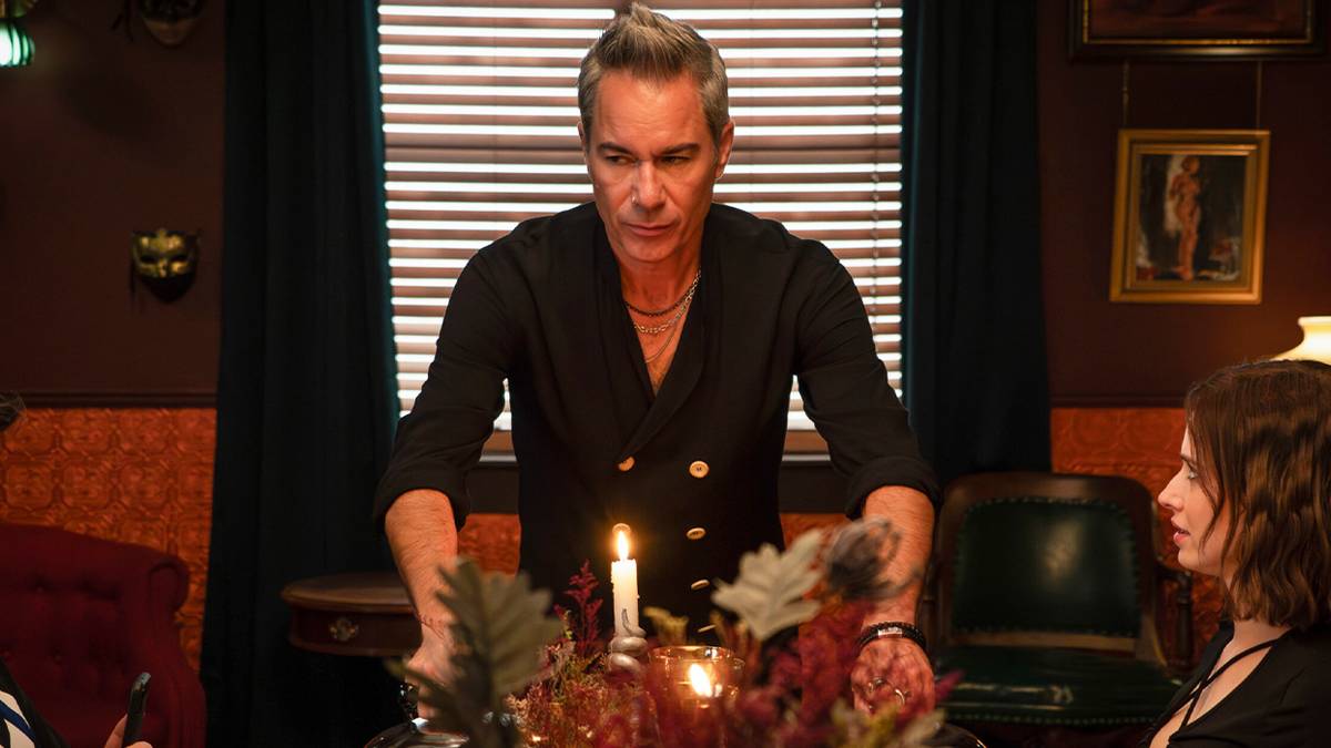 Eric McCormack at the head of a dinner table in Hell Motel