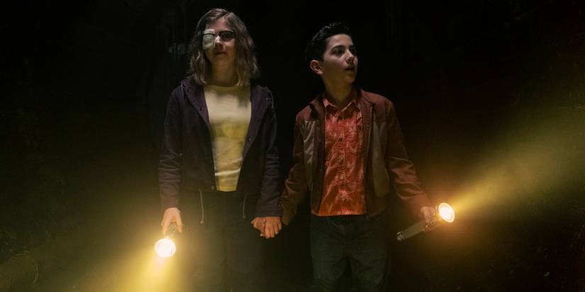 Arian S. Cartaya as Rich holding hands in the sewers with Matilda Lawler as Marge in IT: Welcome to Derry.