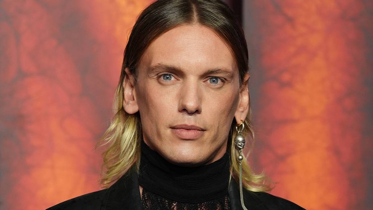 Jamie Campbell Bower smiling on the red carpet. 