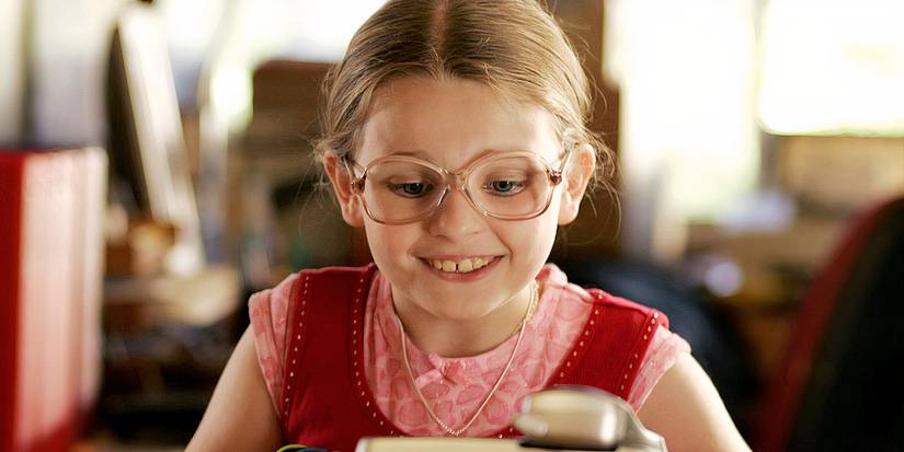 Abigail Breslin wearing glasses smiles while looking down in Little Miss Sunshine