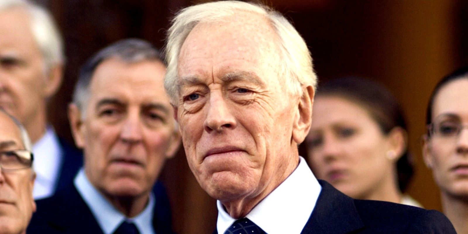 Max Von Sydow standing in a crowd of suited men in Rush Hour