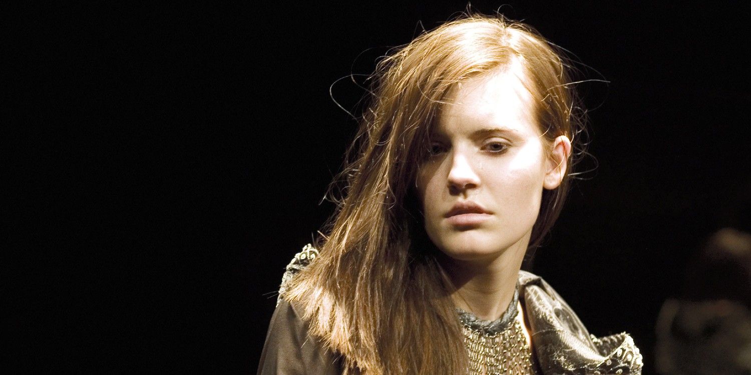 Maggie Grace looks despondent in a dress in a spotlight in Taken