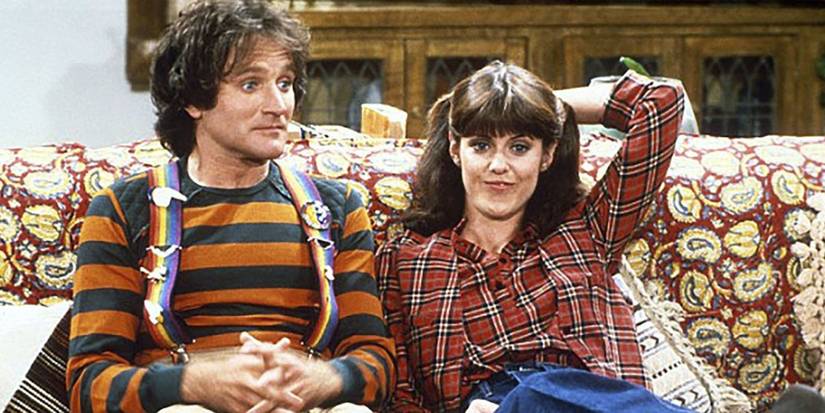 Mork (Robin Williams) and Mindy (Pam Dawber) sitting on the couch in 'Mork & Mindy'