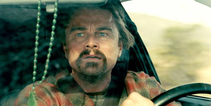 Leonardo DiCaprio driving a car and looking in the rearview mirror in One Battle After Another