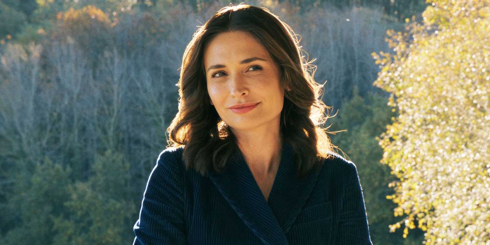 Karolina Wydra outdoors, smiling slightly while glancing to the side in Pluribus Episode 2.