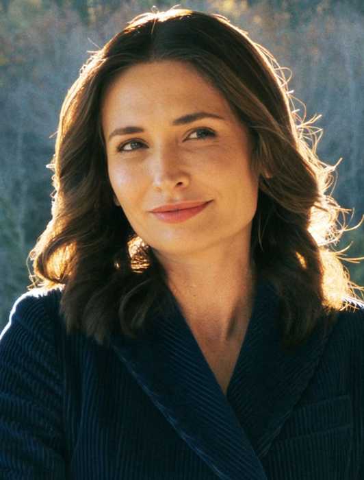 Karolina Wydra outdoors, smiling slightly while glancing to the side in Pluribus Episode 2.