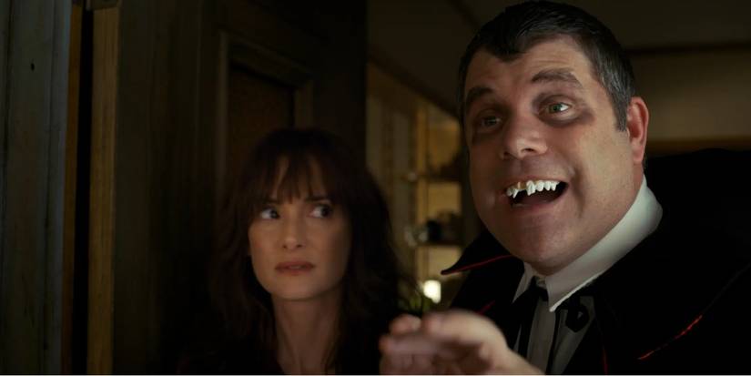 Winona Ryder as Joyce looks at Sean Astin as Bob in a vampire costume with scary teeth on Stranger Things.