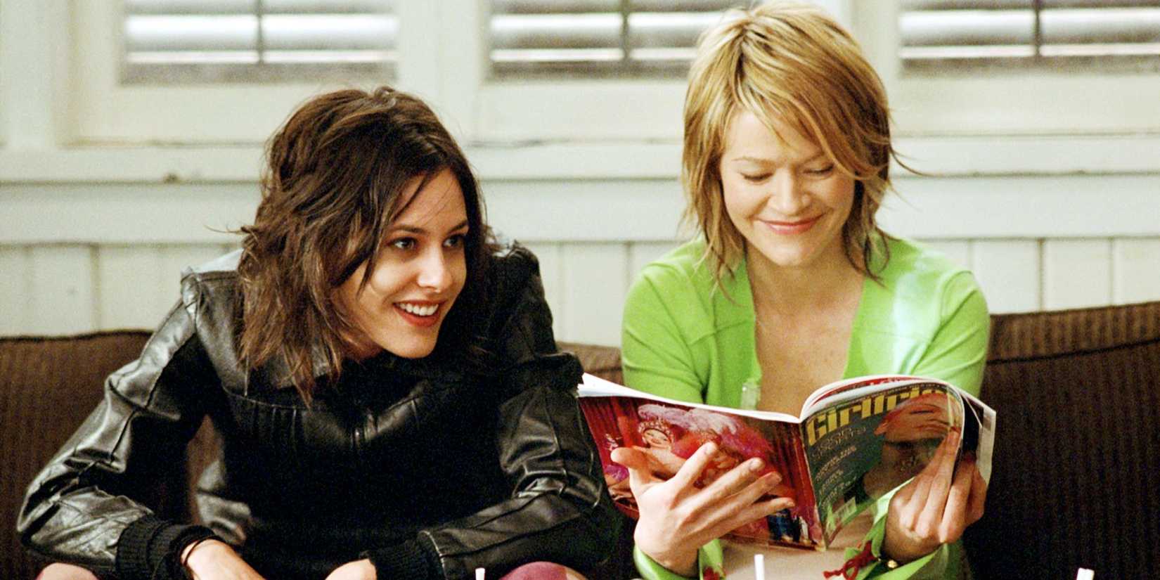 Katherine Moennig and Leisha Hailey sit next to each other on a couch in The L Word.