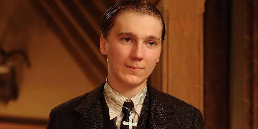 Paul Dano as Eli Sunday with a cross necklace and slicked back hair looking ahead in There Will Be Blood.