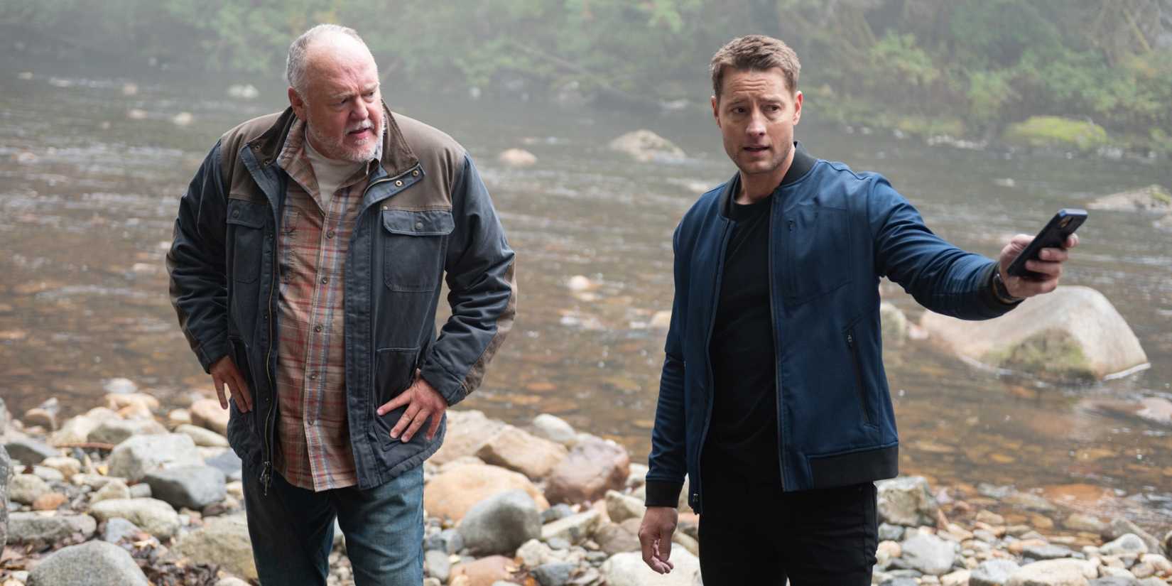 Justin Hartley as Colter Shaw holding his cell phone while standing with Brent Sexton as Keaton in Tracker