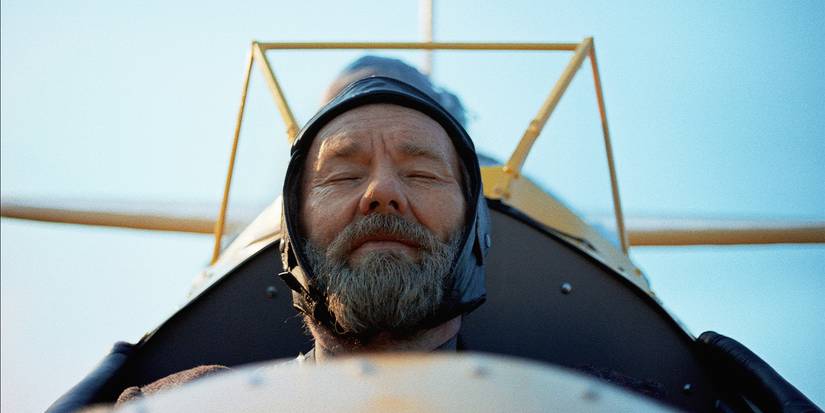 Robert is sitting in an airplane, smiling with his eyes closed.